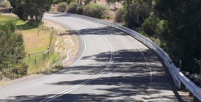 Motorcycle rub rail along a road curving to the left.