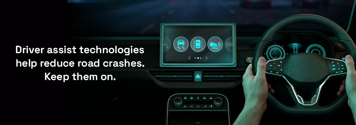 Image of hands on a driving wheel and driver assist technologies displayed on a large display.