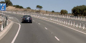 A double-lane road with wide, 1.5 m shoulders and roadside barriers